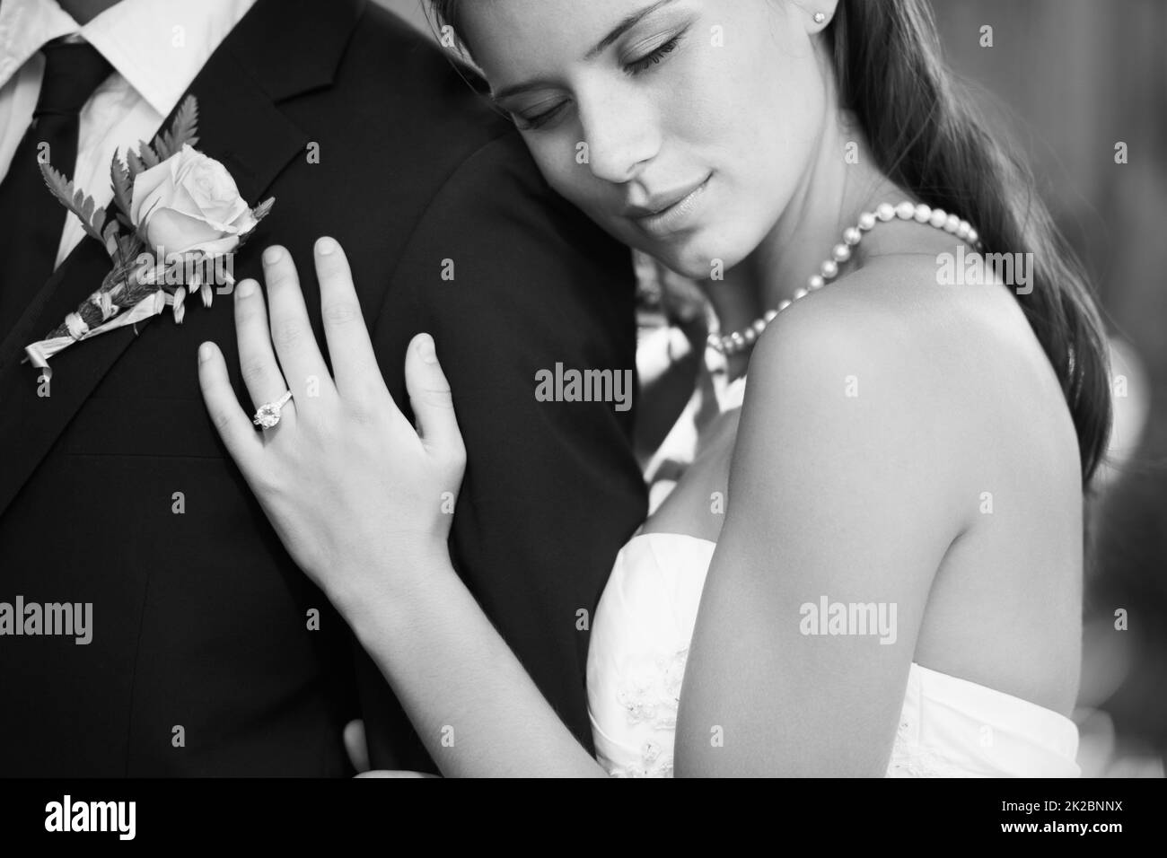 Träumen in Schwarz und Weiß. Schwarz-weißes Bild einer schönen Braut, die ihren Mann von hinten liebevoll umarmt. Stockfoto