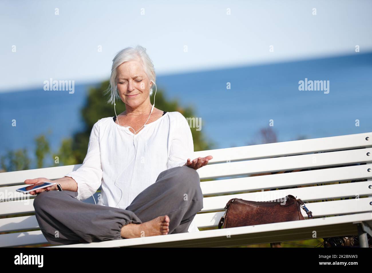 Entspannen Sie sich bei ruhiger Musik. Aufnahme einer reifen Frau, die während einer Entspannungsübung im Freien Musik hört. Stockfoto