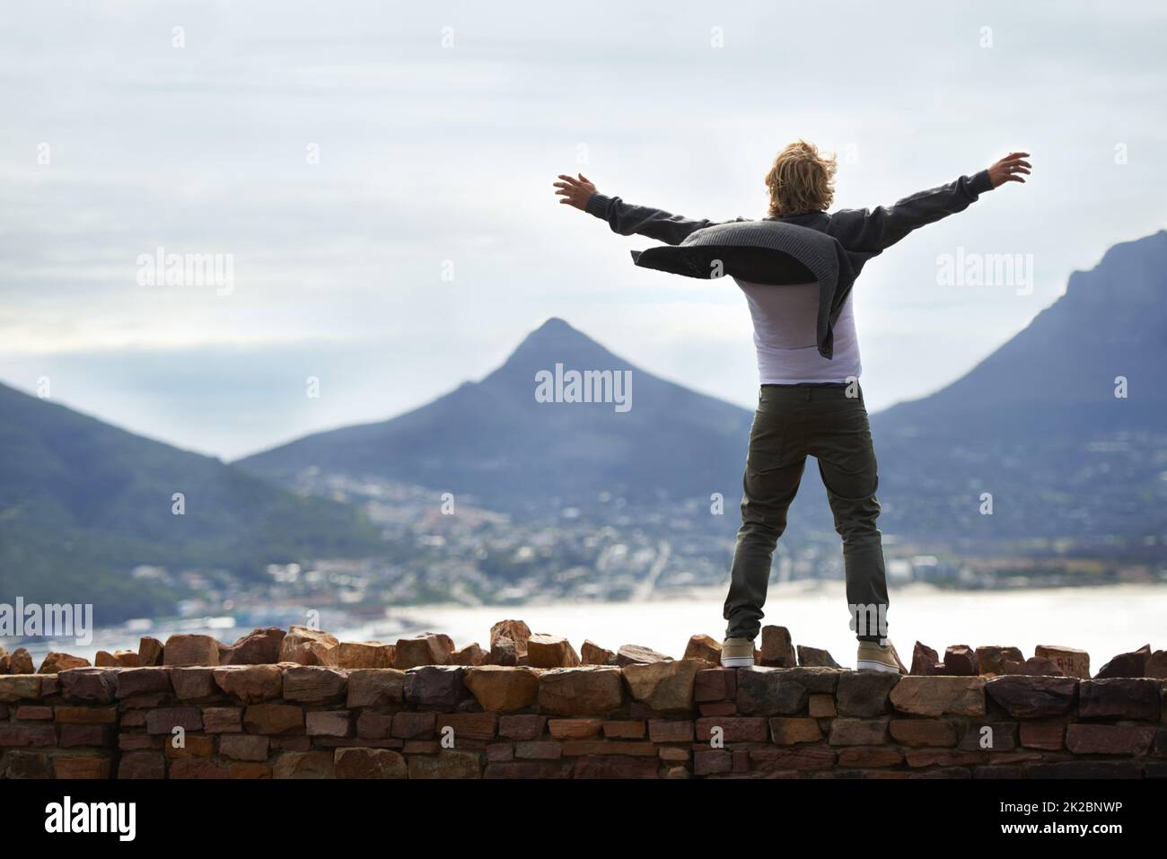 Was für ein Tag, um am Leben zu sein. Aufnahme eines jungen Mannes, der an einer Wand steht und die natürliche Landschaft betrachtet. Stockfoto