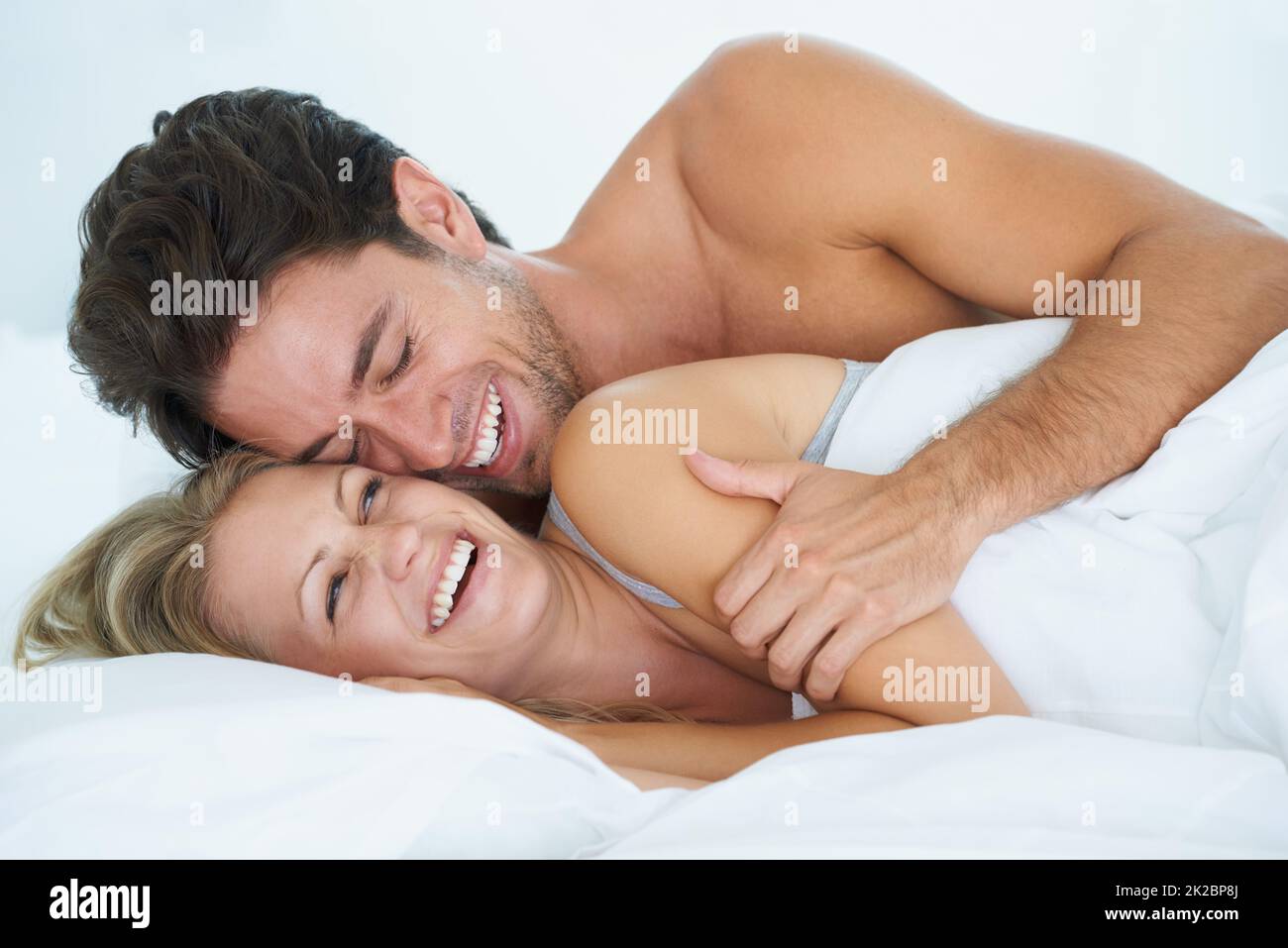 Magische Morgen zusammen. Ein Mann umarmt seine Frau liebevoll, während er zusammen im Bett liegt. Stockfoto