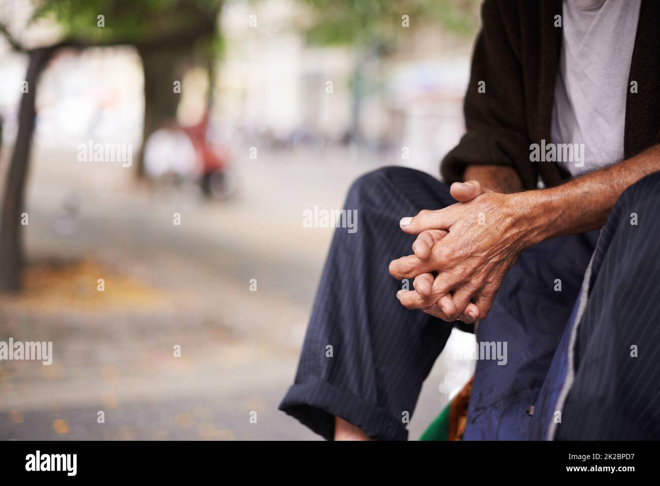 Ältere Menschen in der Stadt. Kurzer Schuss eines alten Mannes, der draußen sitzt. Stockfoto