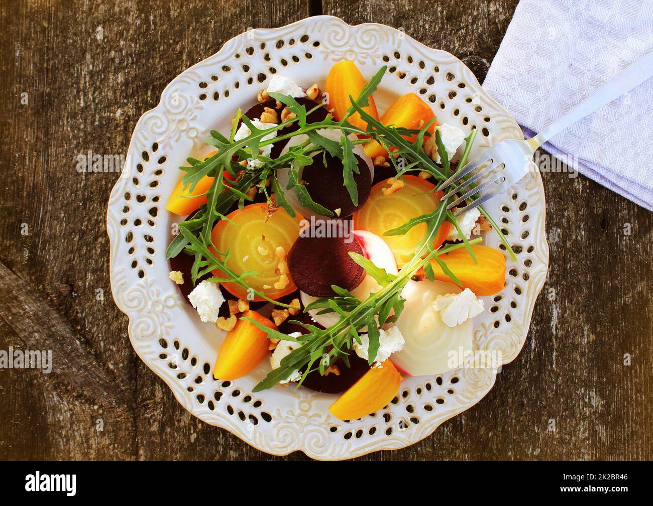 Gesunde Rüben Salat mit roten, weißen und goldenen Rüben, Rucola, Muttern, Feta Käse auf Holz- Hintergrund Stockfoto