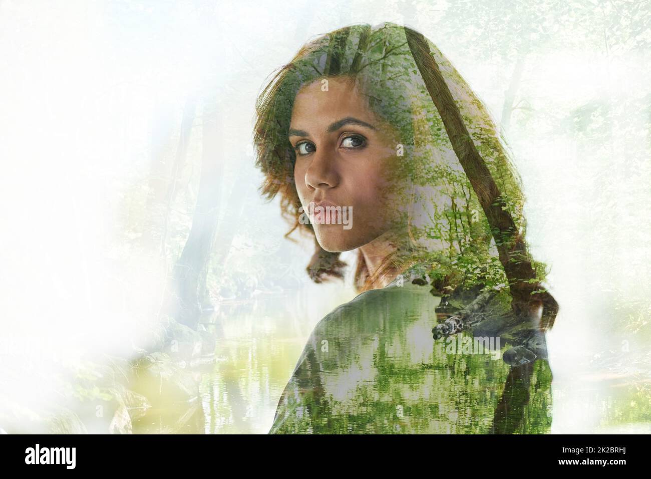 Die Eroberung des Betondschungels. Mehrfachaufnahme einer jungen Geschäftsfrau über einer Waldlandschaft. Stockfoto