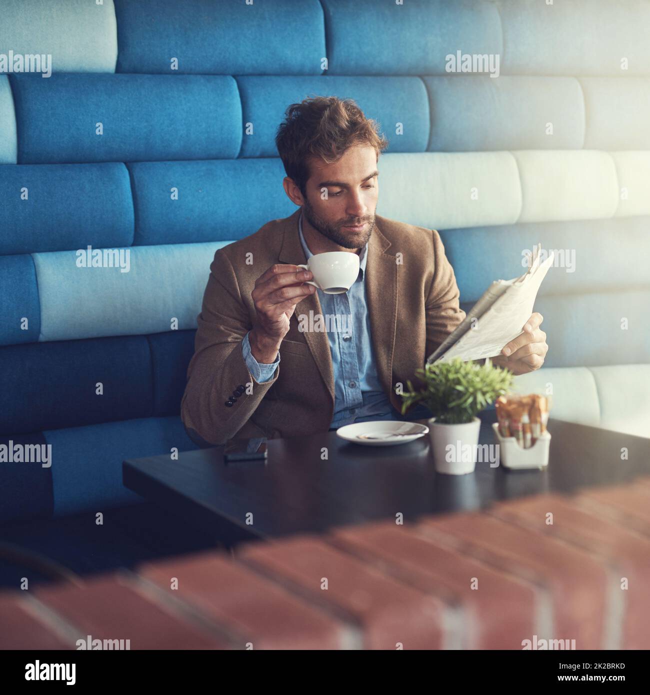 Er mag seine Nachrichten in der Presse. Aufnahme eines hübschen Mannes, der bei einer Kaffeepause in einem Café eine Zeitung liest. Stockfoto