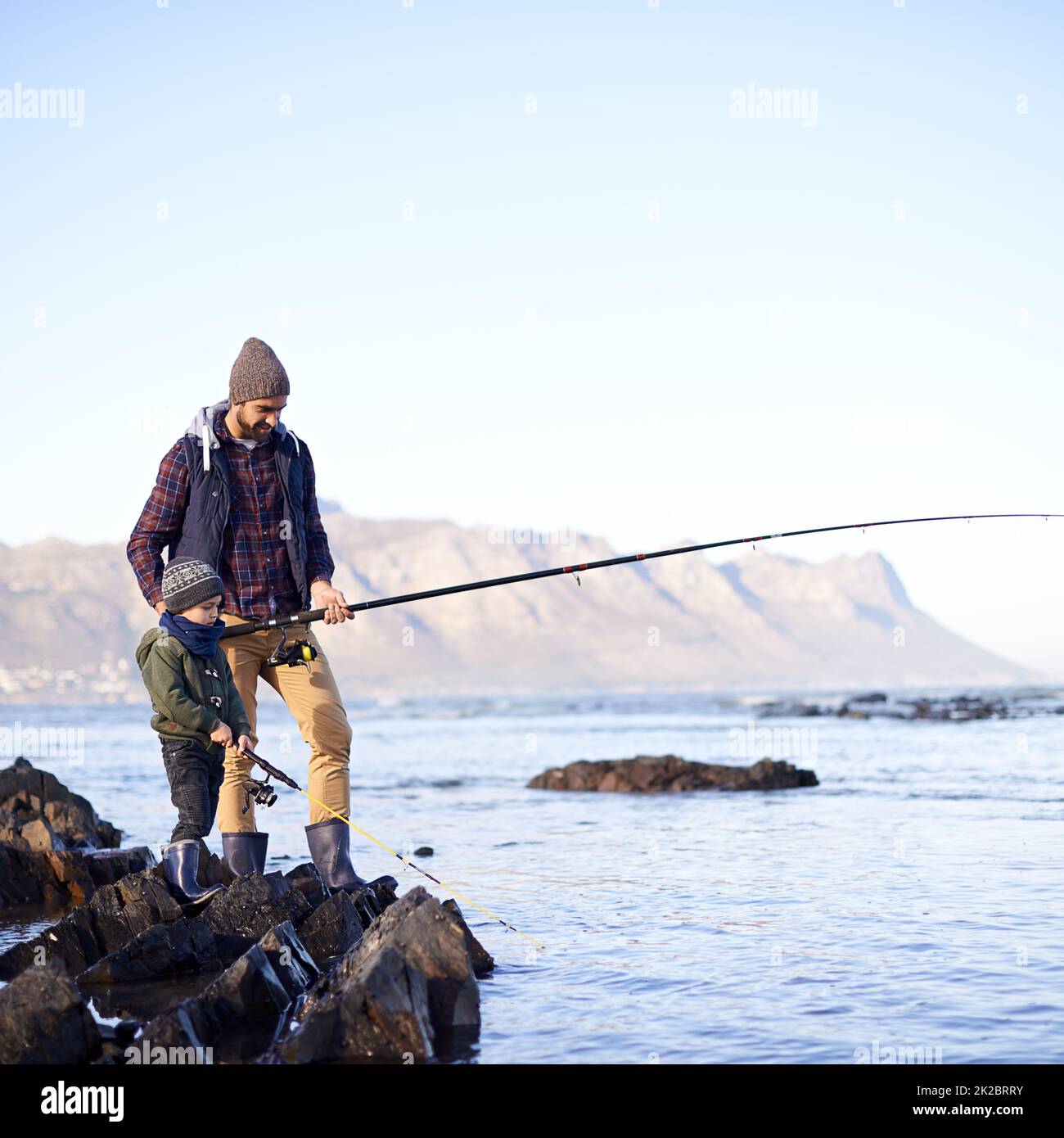 Es sieht so aus, als ob du etwas hast. Aufnahme eines niedlichen kleinen Jungen, der mit seinem Vater am Meer fischt. Stockfoto