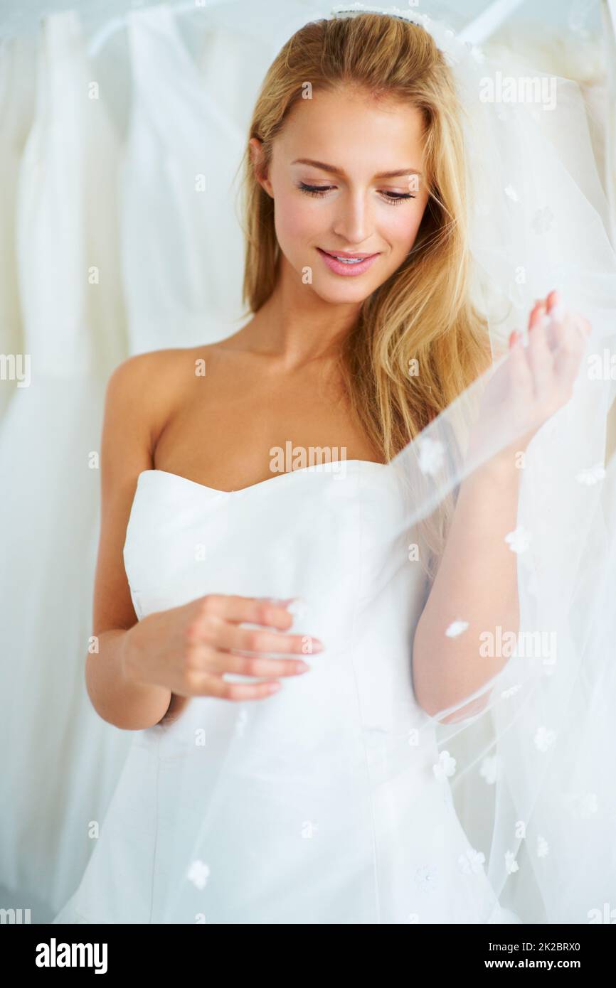 Mit Begeisterung an ihre Zukunft denken. Eine junge Braut versucht sich ein Hochzeitskleid an. Stockfoto