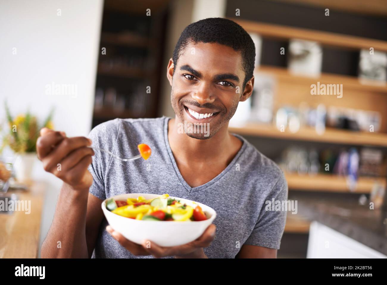 Haben Sie einen Bissen Gesundheit. Innenaufnahme eines wunderschönen jungen schwarzen Mannes, der seinen Obstsalat vorführt. Stockfoto