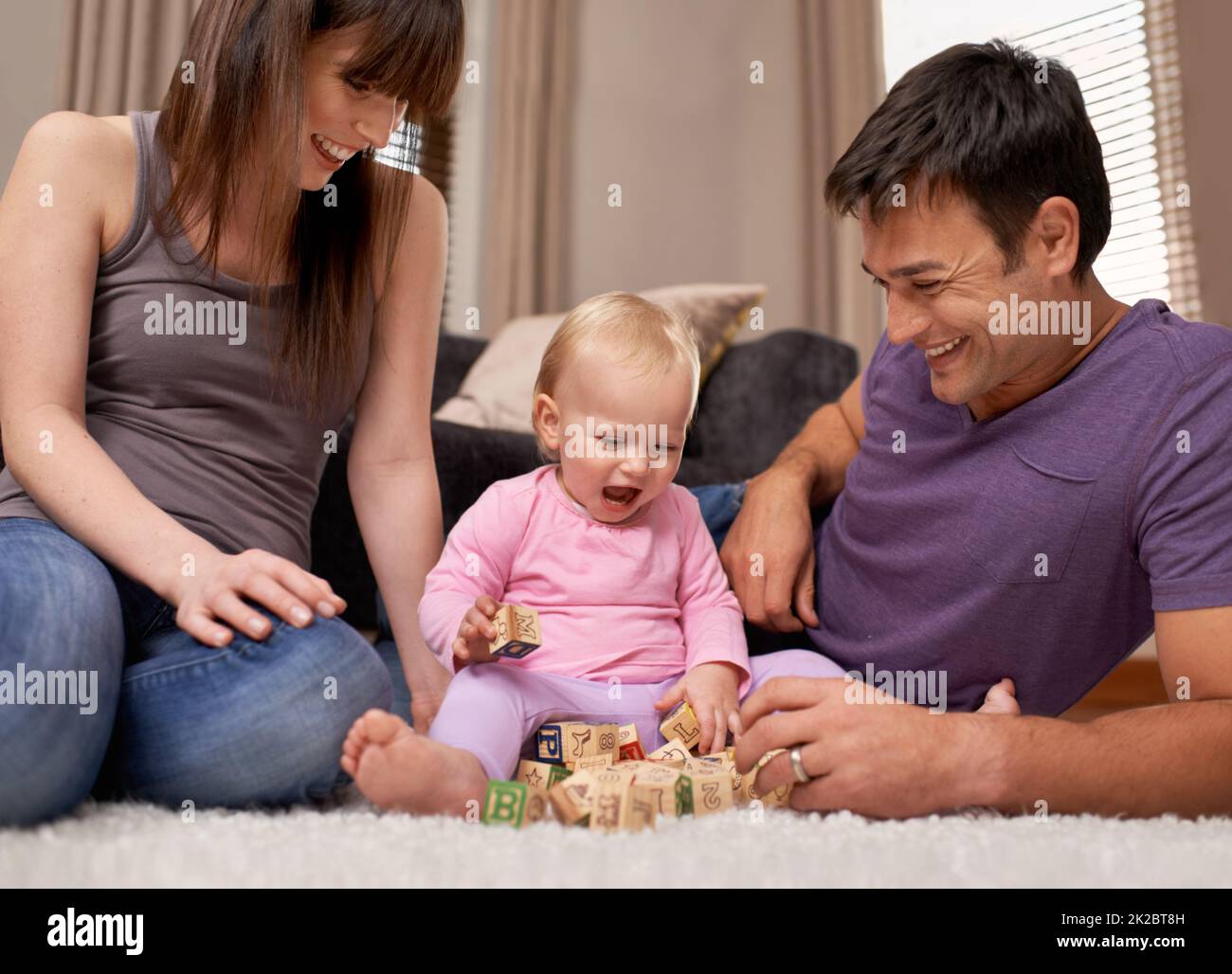 Aufgewachsen unter der Anleitung ihrer Eltern. Aufnahme eines jungen Paares, das ihre kleine Tochter beim Spielen beobachtete. Stockfoto