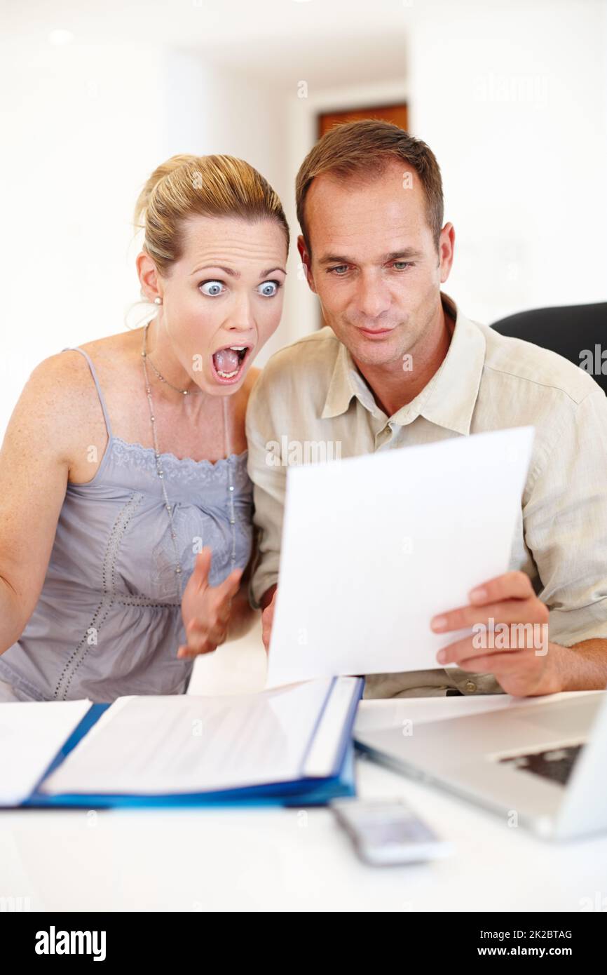 Budgetübertraf. Aufnahme eines Paares, das sich mit einem Laptop vor sich den Papierkram ansah. Stockfoto