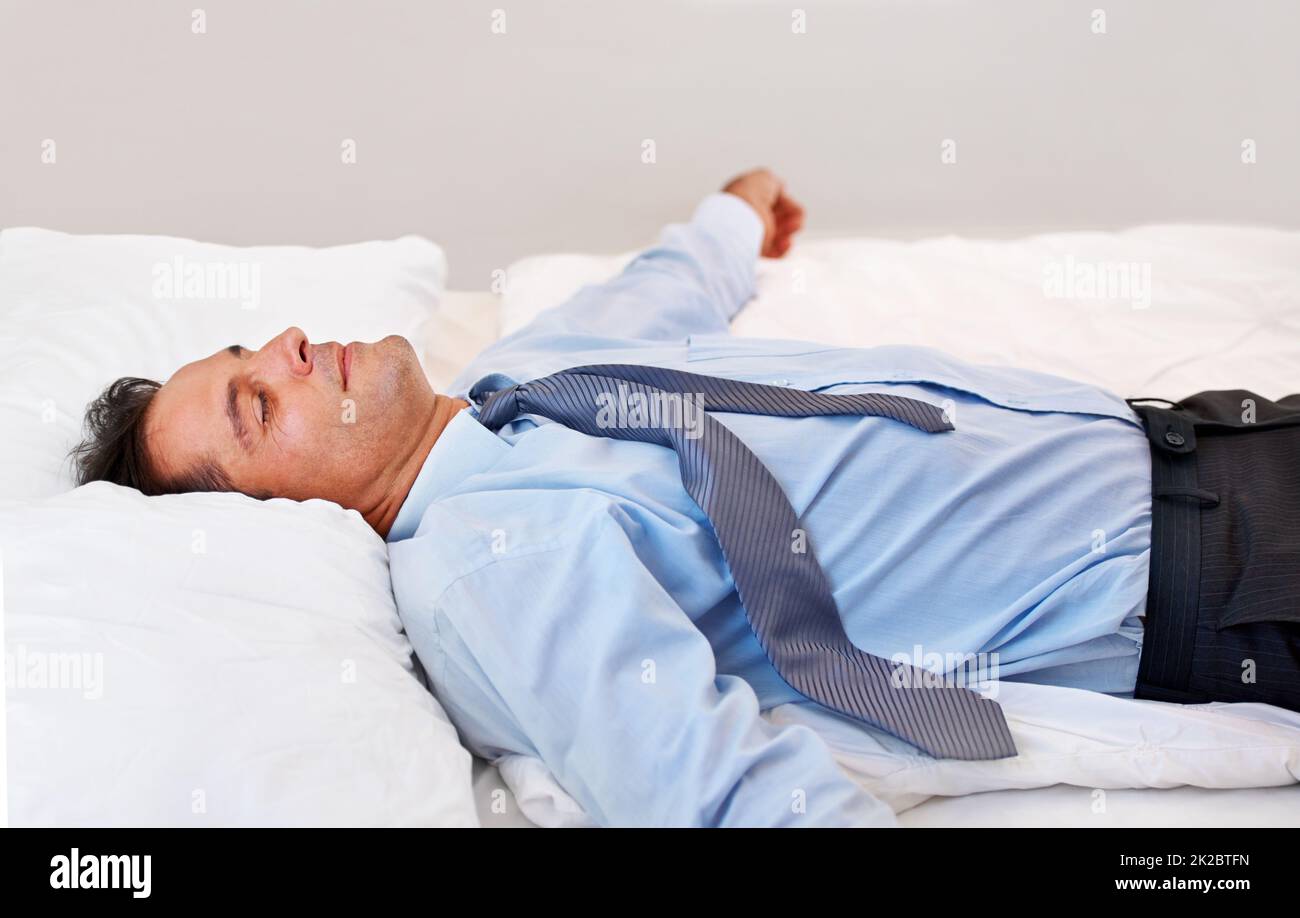 Absolute Erschöpfung. Ein Geschäftsmann lag völlig erschöpft auf seinem Bett. Stockfoto