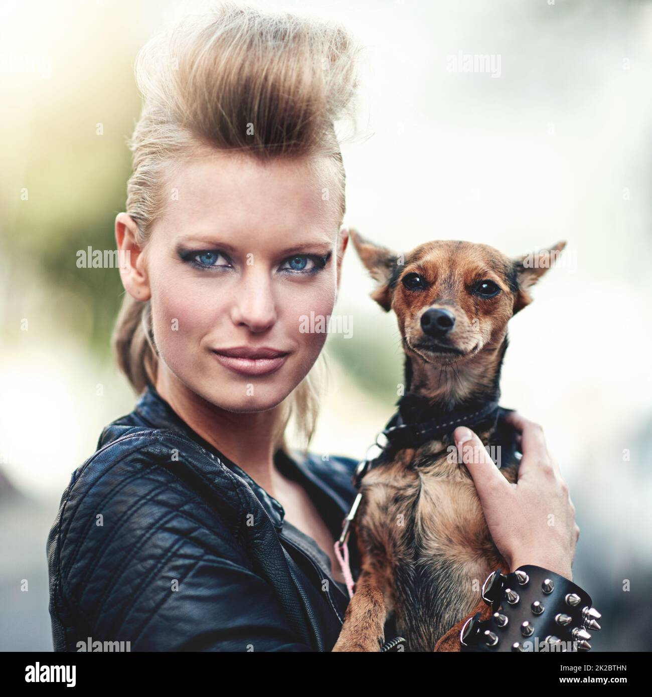 Hes ist ein Rockstar. Beschnittenes Porträt einer kantigen jungen Frau, die ihren kleinen Hund im Freien hält. Stockfoto