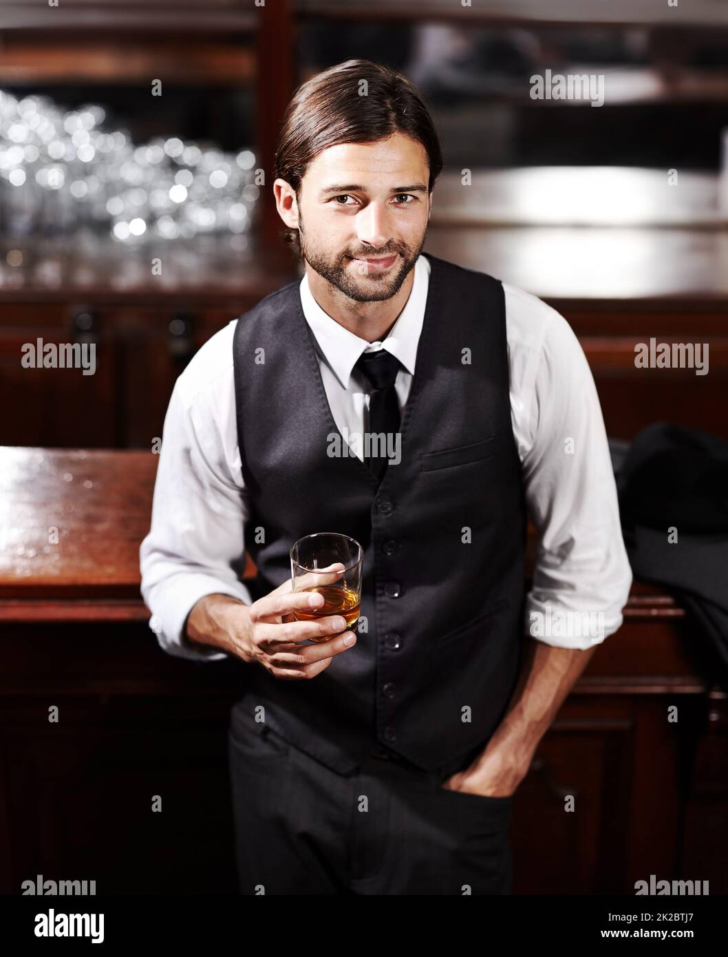 Es ist einfach. Porträt eines gut gekleideten jungen Mannes, der bei einem Drink an einer Bar sitzt. Stockfoto