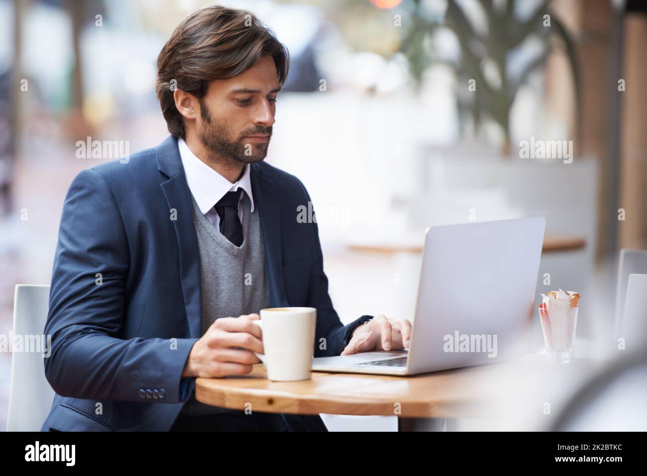 Kaffeekonzentration. Ein gutaussehender Geschäftsmann, der in einem Coffeeshop an seinem Laptop arbeitet. Stockfoto