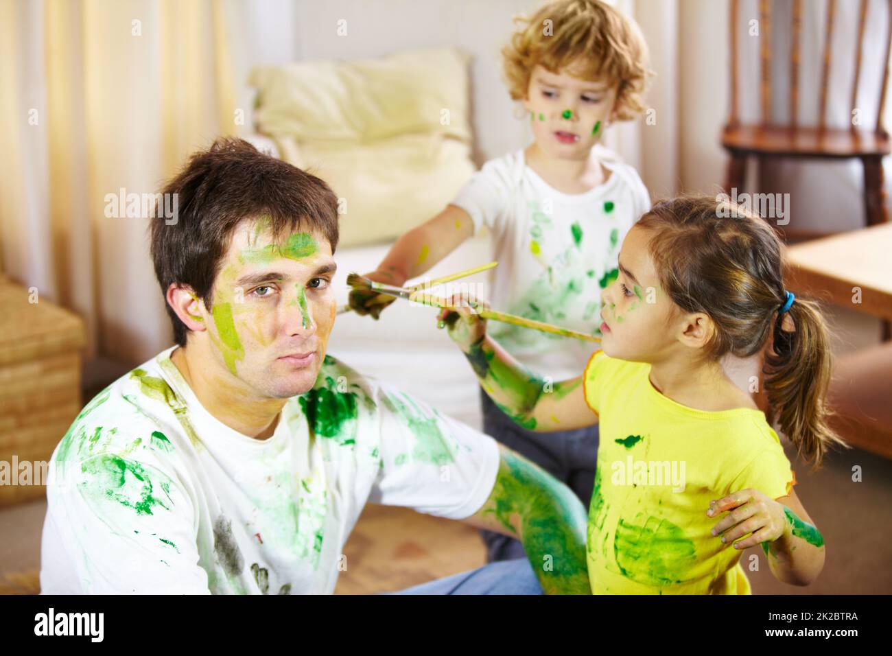 Babysitting ist nichts für schwache Nerven. Aufnahme eines Vaters, der von seinen Kindern gemalt wurde. Stockfoto