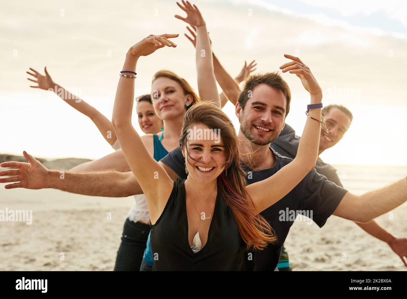 Viele Körper, ein Herz. Porträt einer Gruppe von glücklichen jungen Freunden, die zusammen mit ihren Armen am Strand aufposieren. Stockfoto