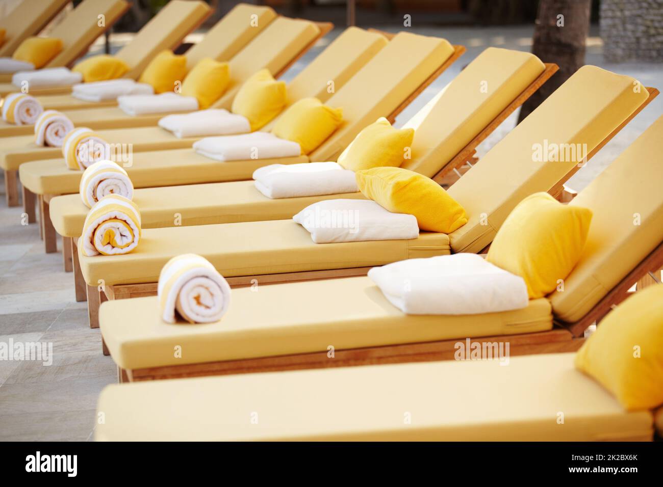 Liegestühle in einer Reihe. Blick auf eine Reihe von gelben Liegestühlen des Resorts. Stockfoto