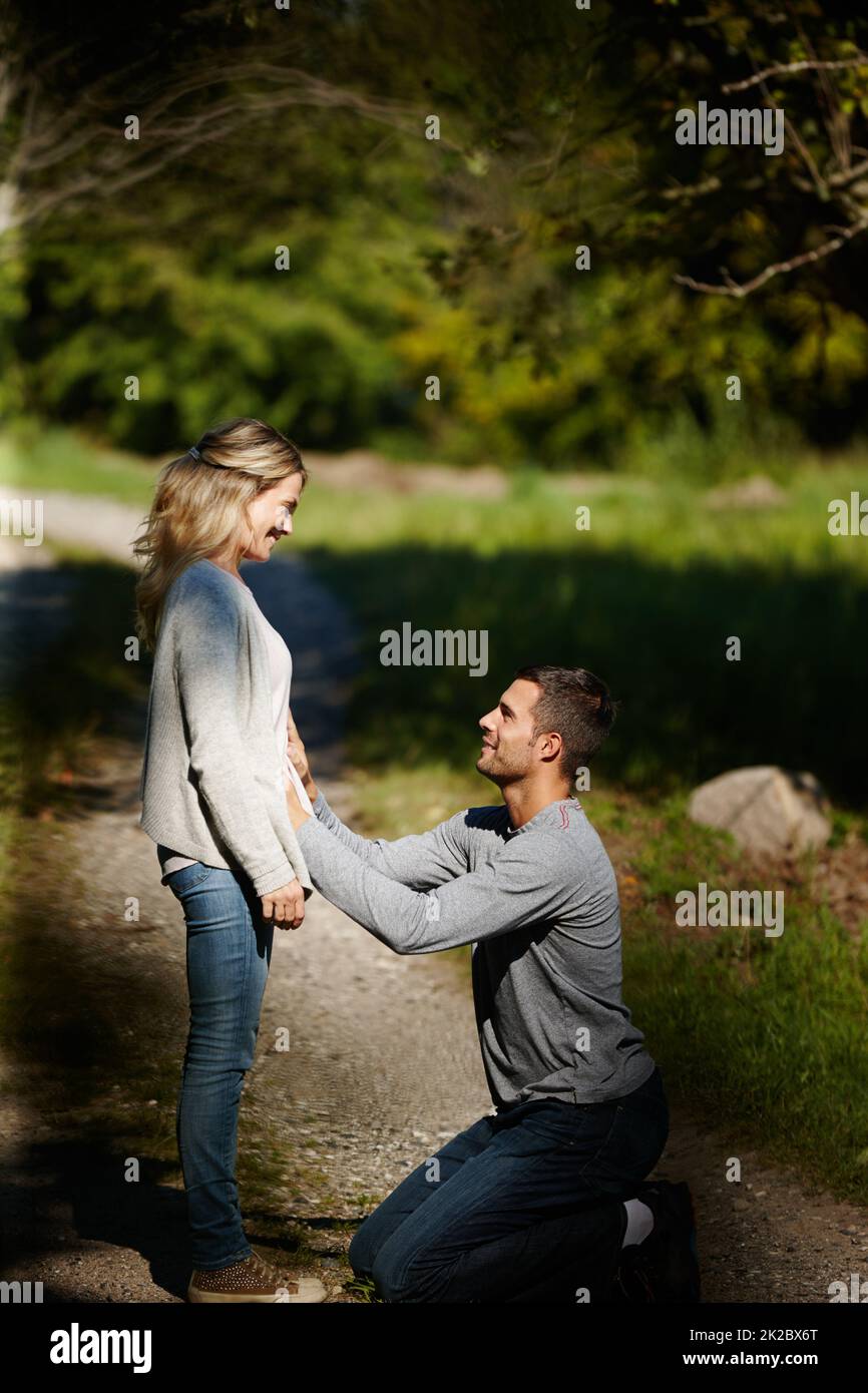 Würden Eltern sein. Aufnahme eines Mannes, der kniet und den Bauch seiner Frau berührt, während er einen Tag im Park genießt. Stockfoto