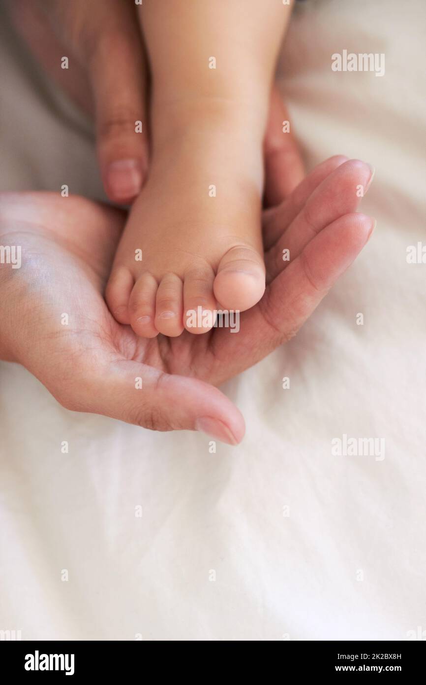 Seine Fußstapfen führen. Beschnittenes Bild einer Mutter, die die Hände ihres kleinen Jungen am Fuß hält. Stockfoto