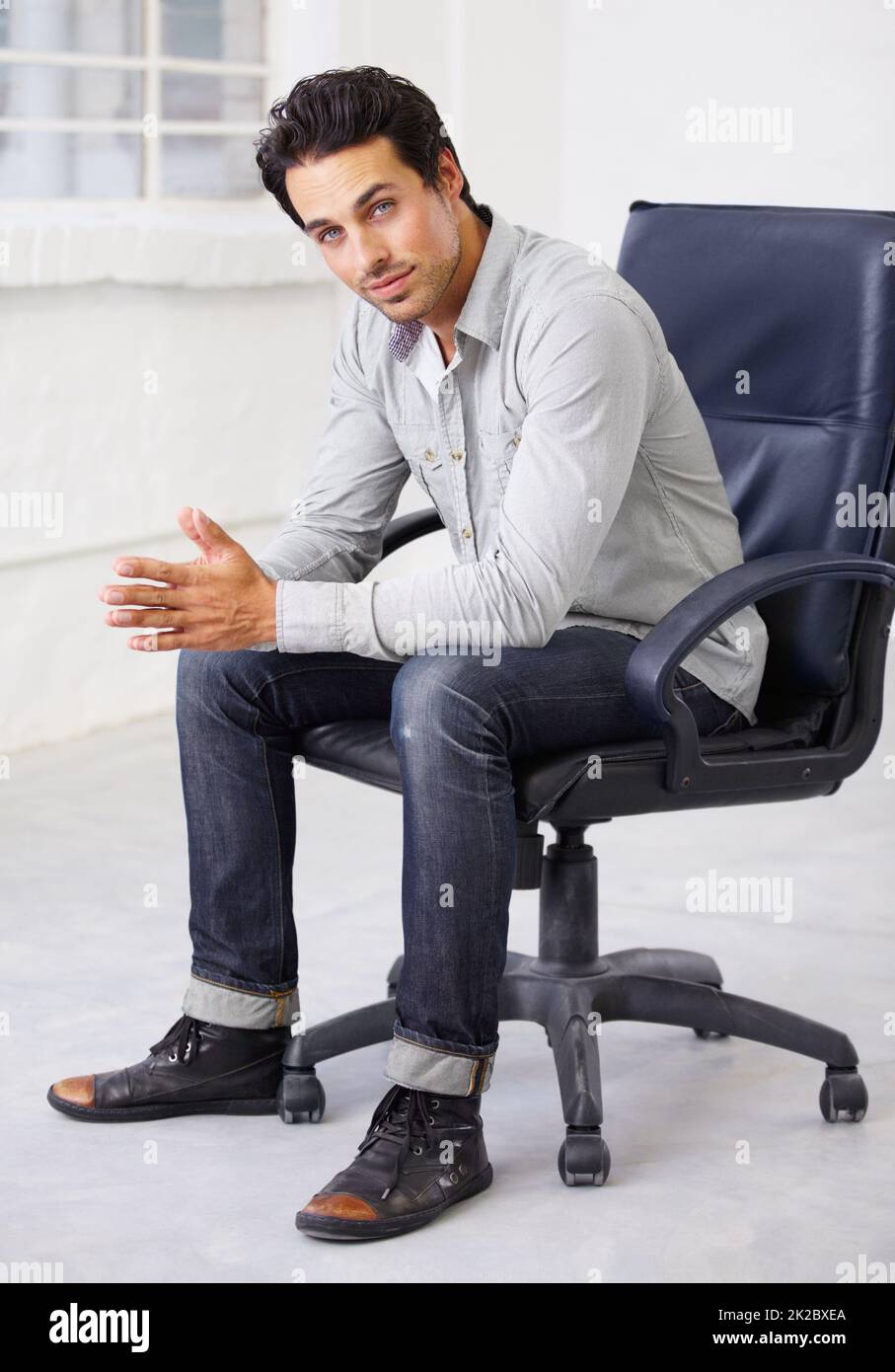Jung, hübsch und stilvoll. Aufnahme eines hübschen Jungen, der auf einem Stuhl sitzt. Stockfoto