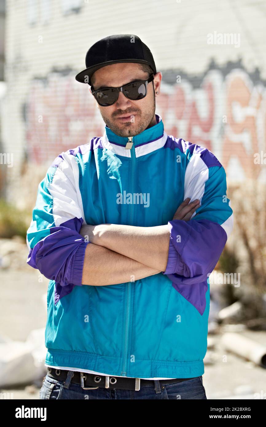 Ich liebe meinen Stil. Ein Hip-Hop-Männchen mit einer Mütze und einer Sonnenbrille, die vor einer Graffiti-Wand steht. Stockfoto