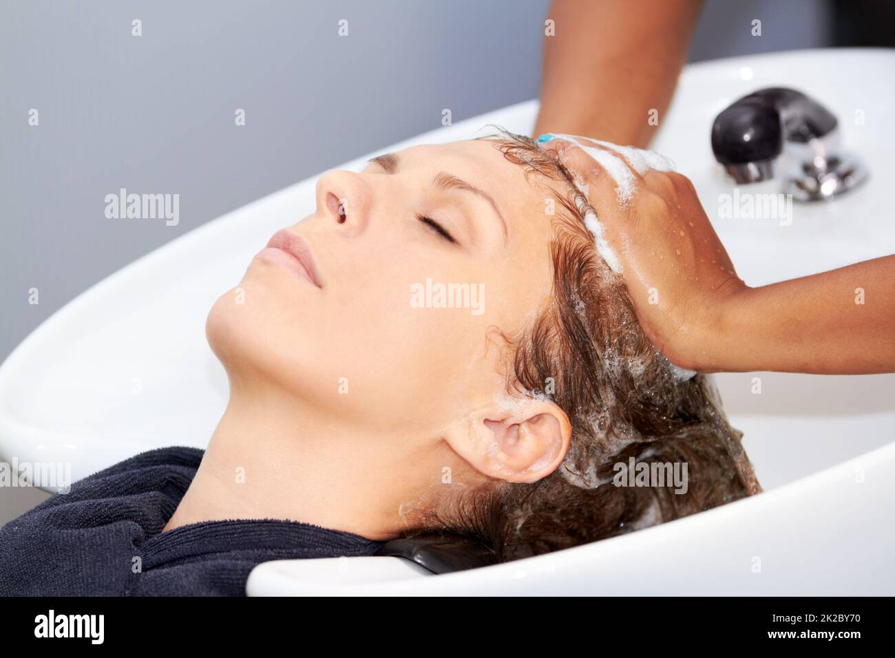 Ich liebe es, meine Haare zu waschen. Eine attraktive junge Frau, die sich beim Friseur die Haare waschen ließ. Stockfoto