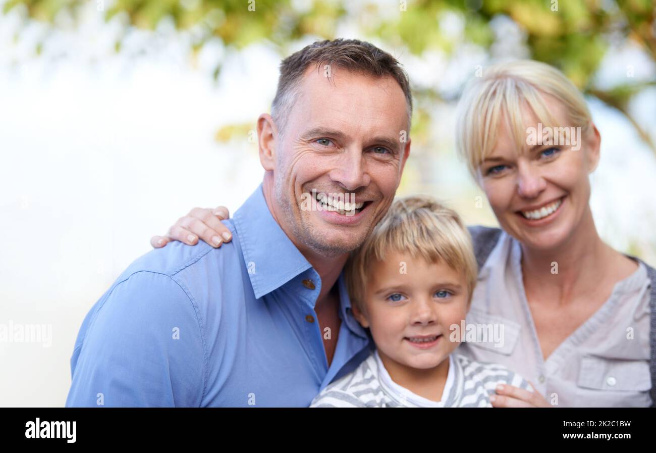 Wir lieben unseren kleinen Jungen. Ein süßer kleiner Junge, der von seinen Eltern im Freien flankiert wird. Stockfoto