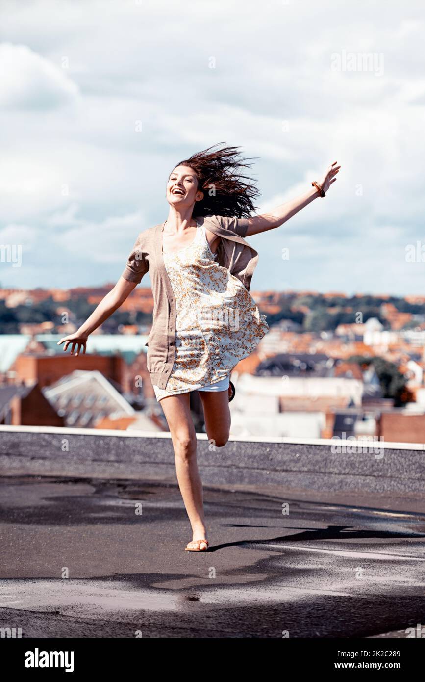 Loslassen und das Leben zu leben. Hübsche junge Frau, die auf einem Dach whimsically tanzt. Stockfoto