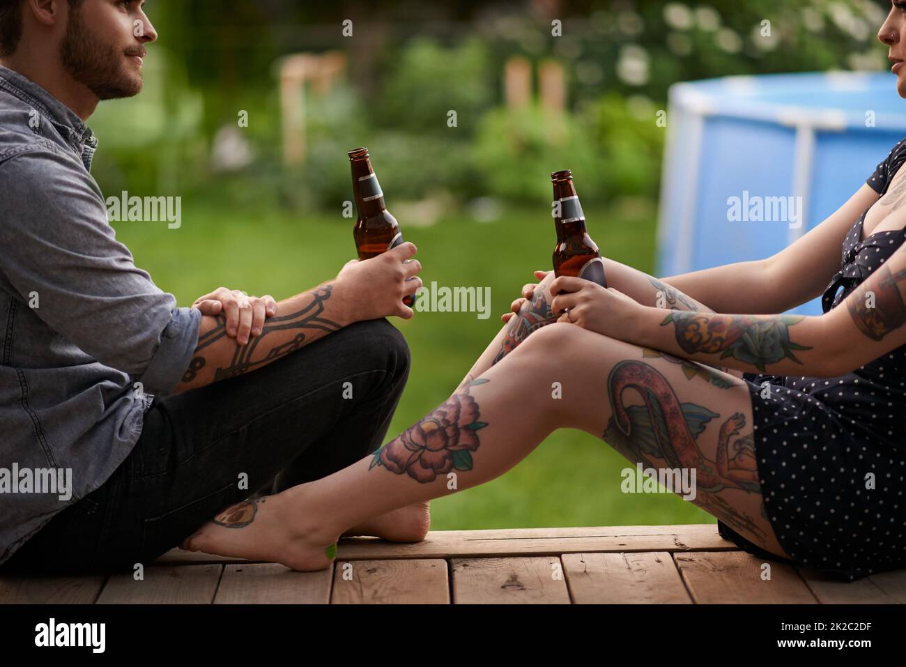 Jedes Tattoo hat eine Geschichte. Aufnahme eines jungen Paares, das zusammen auf der Veranda ein paar Drinks genießt. Stockfoto