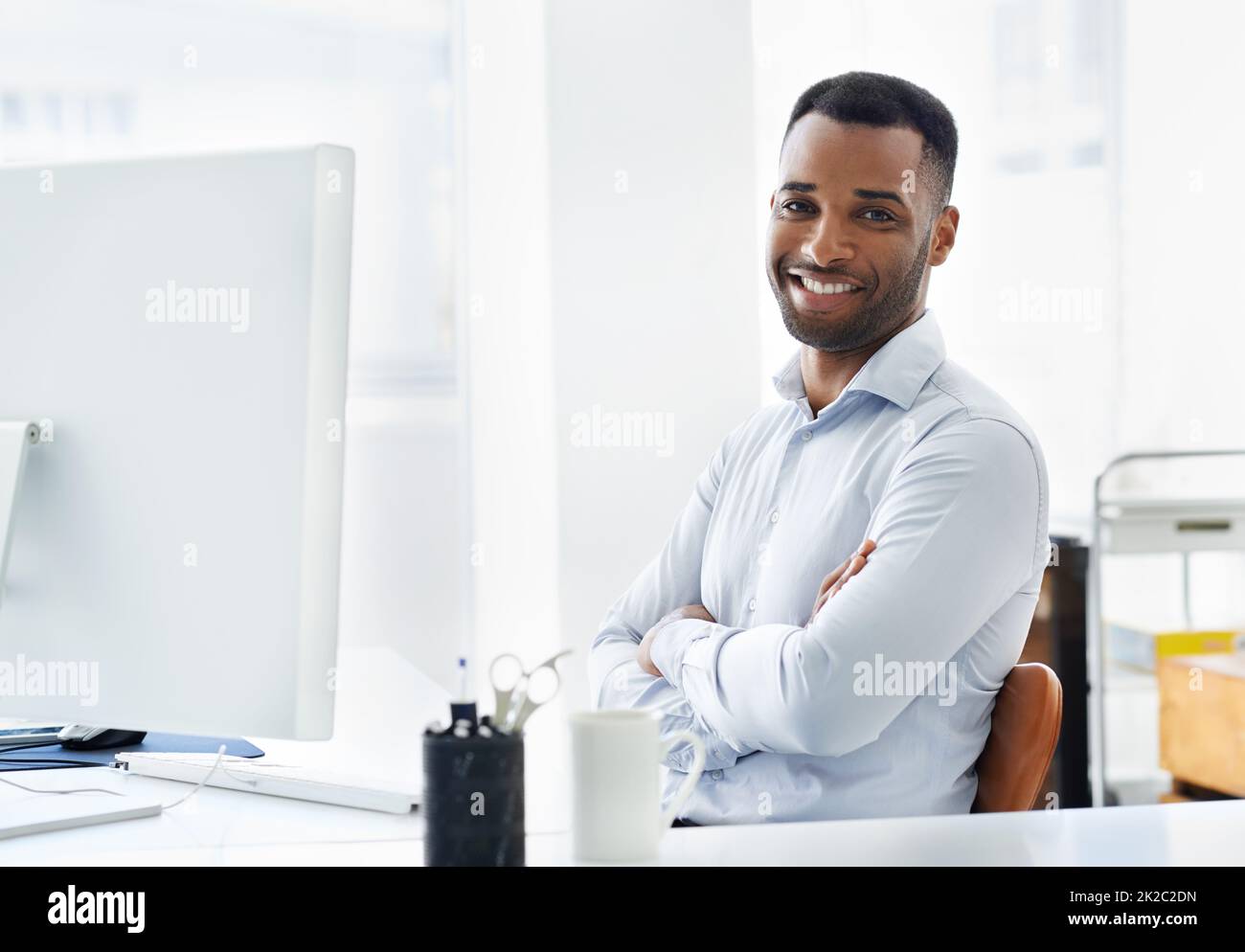 HES zuversichtlich in seine Karriere. Ein hübscher junger afroamerikanischer Geschäftsmann, der an seinem Schreibtisch arbeitet. Stockfoto