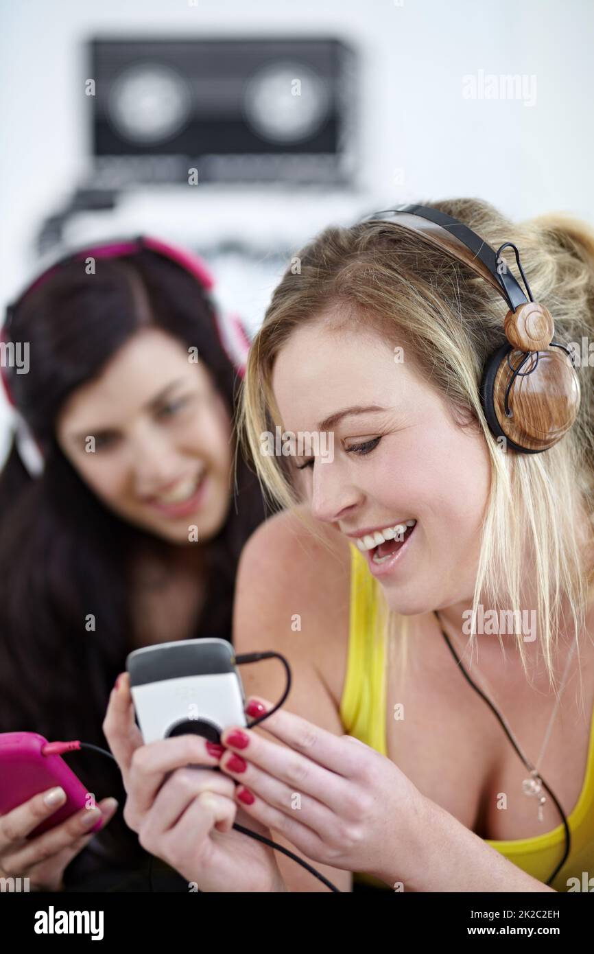 Genießen Sie den Beat. Zwei junge Freundinnen, die gemeinsam Musik auf einem mp3-Spieler hören. Stockfoto