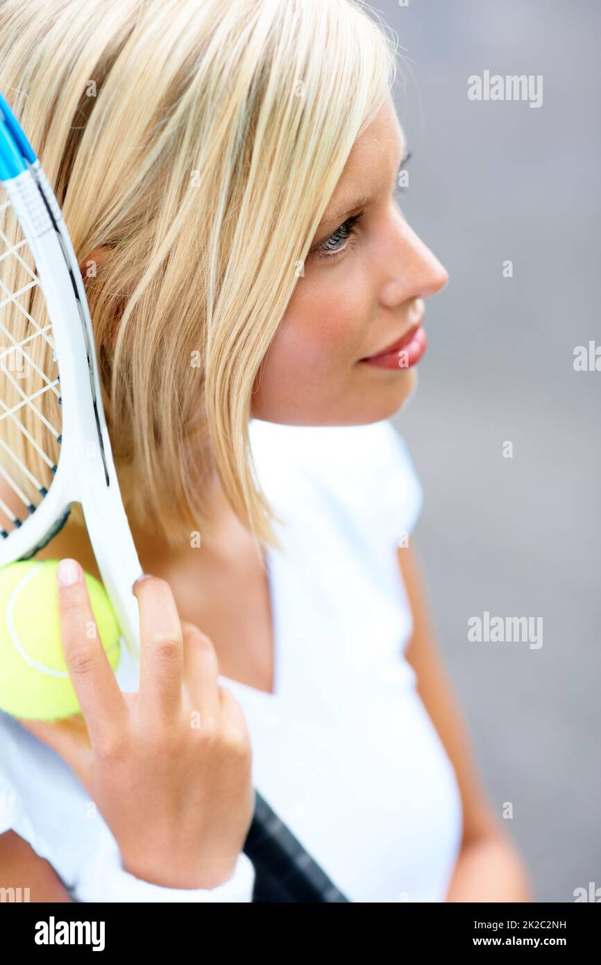 Sich voll und ganz auf den Sieg konzentrieren. Eine junge Tennisspielerin mit Schläger und Ball in der Hand. Stockfoto