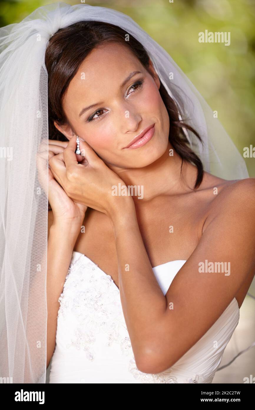 Anpassungen in letzter Minute. Schöne Braut, die ihre Ohrringe an ihrem Hochzeitstag anpasst. Stockfoto