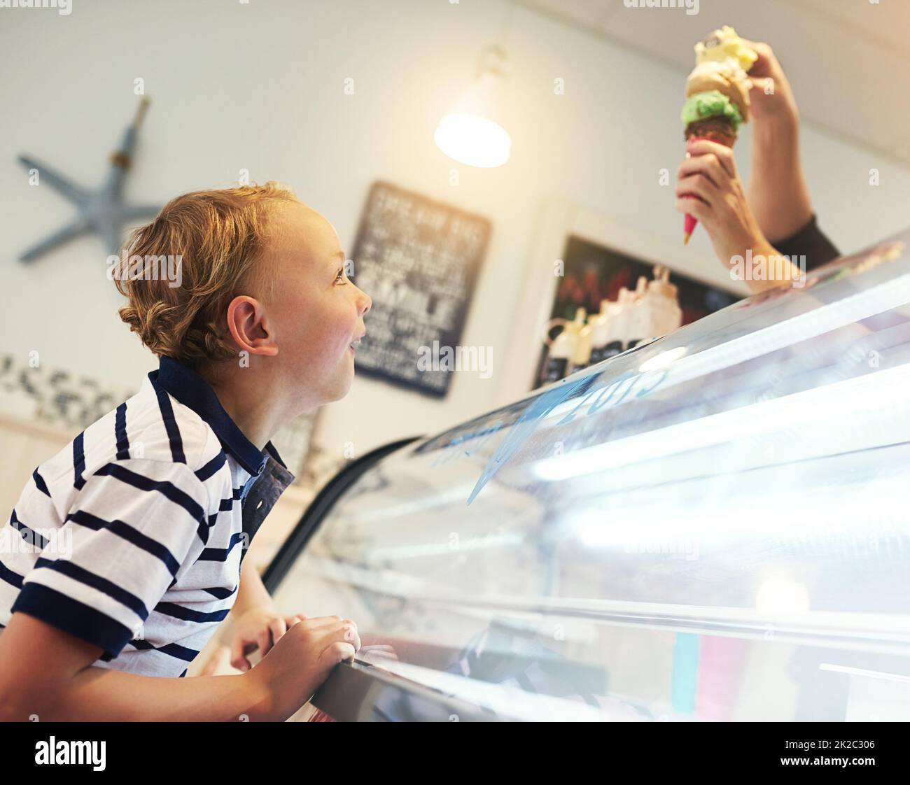 Bitte fünf Messlöffel. Kurzer Schuss eines Jungen, der eifrig auf einen Eiskegel wartet. Stockfoto