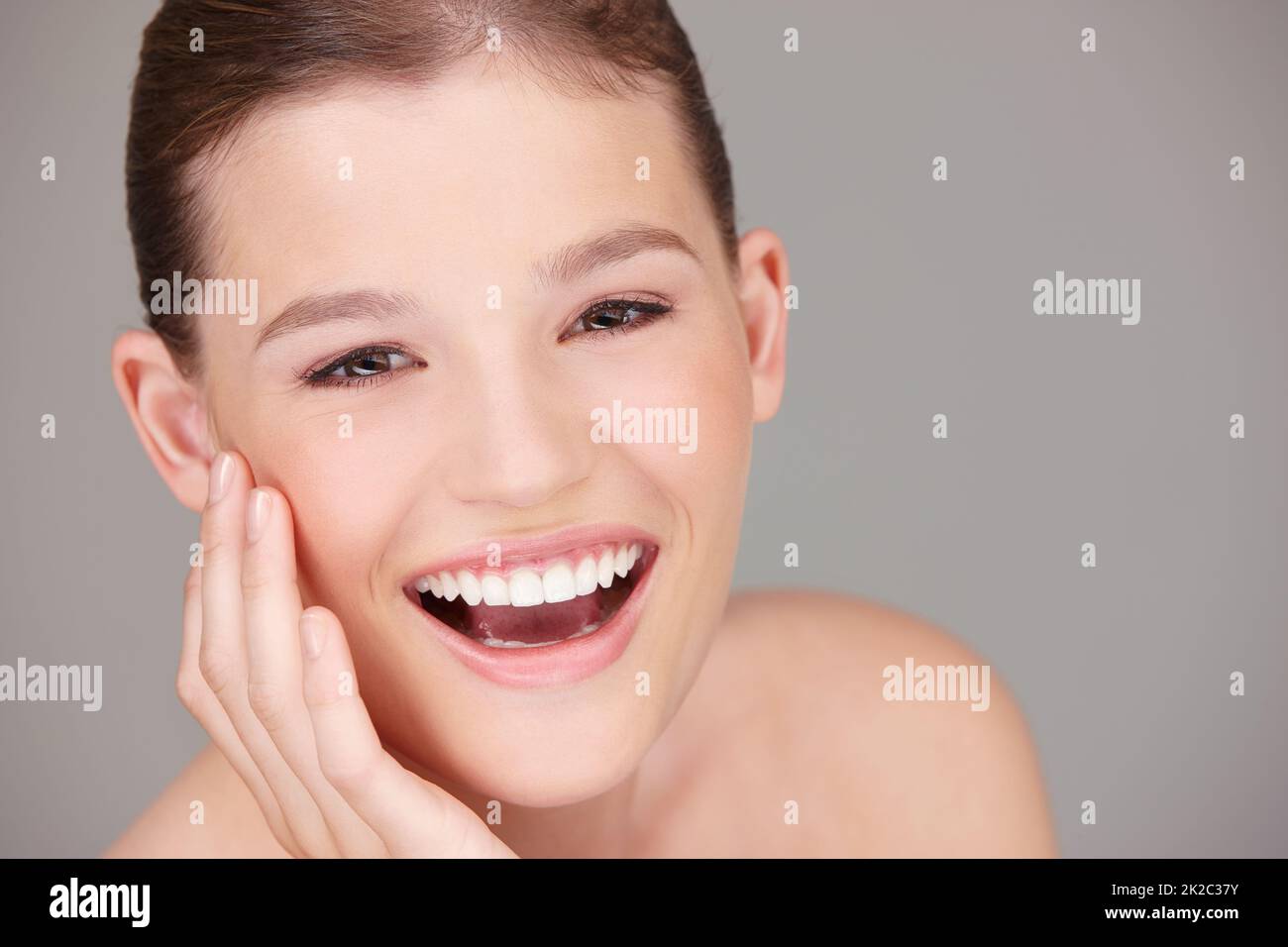 Völlig unfleckig. Studioporträt einer schönen Frau, die ihre Wange streichelt. Stockfoto