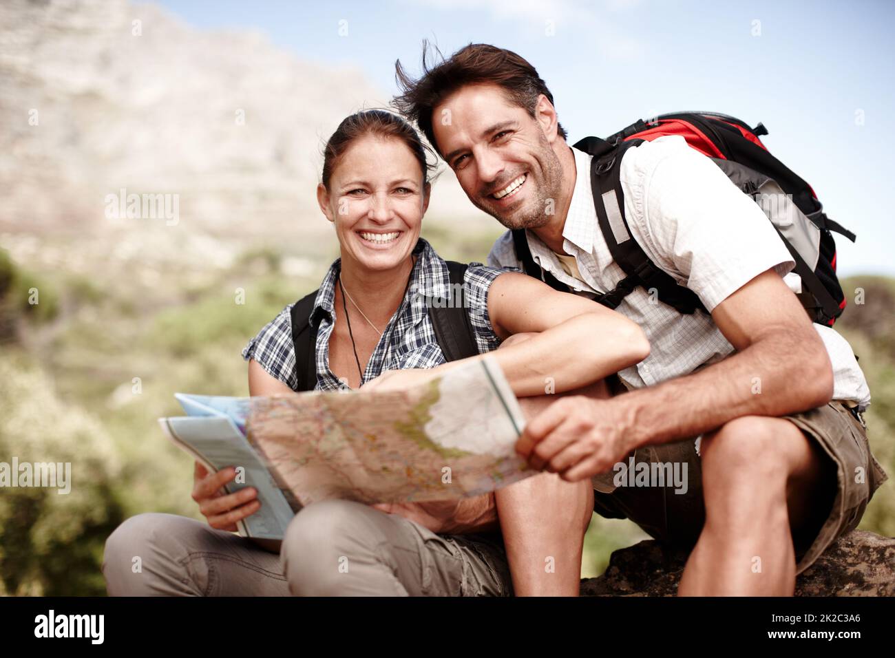 Auf ausgetretenen Pfade. Zwei Wanderer, die ihre Karte konsultieren, während sie auf einem Berggipfel sitzen. Stockfoto