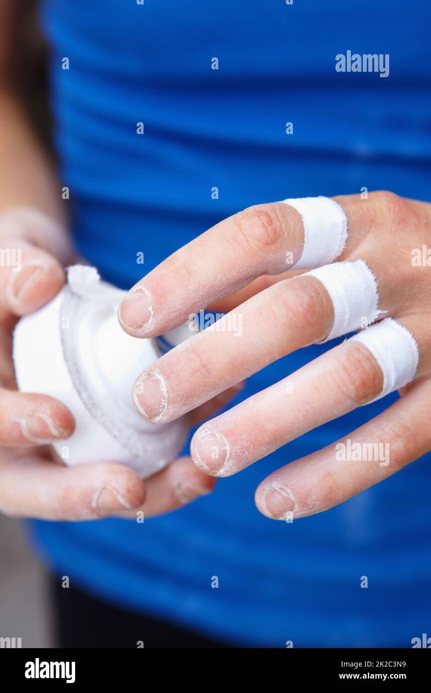 Mit ihren Fingern zukleben. Nahaufnahme einer Bergsteigerin, die ihre Finger zuklebt. Stockfoto