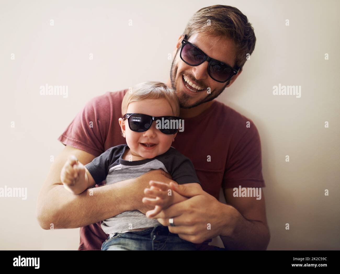 Coolness läuft in dieser Familie. Ein junger Vater und sein kleiner Sohn tragen dazu passende Sonnenbrillen und lachen. Stockfoto