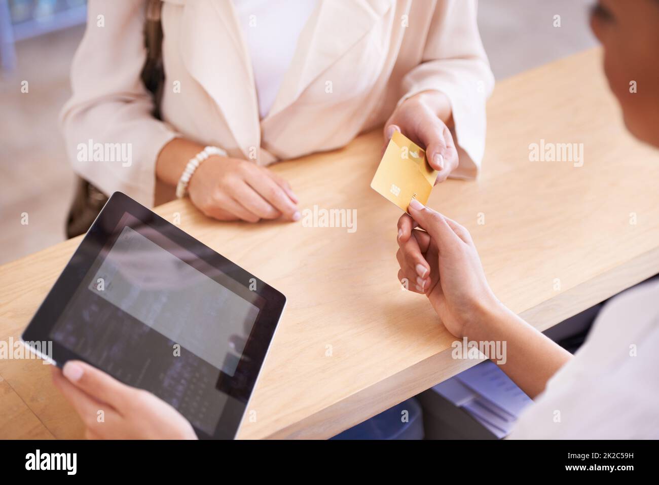 Lade es auf meine Karte. Eine junge Frau, die ihre Kreditkarte einem Verkäufer übergibt. Stockfoto