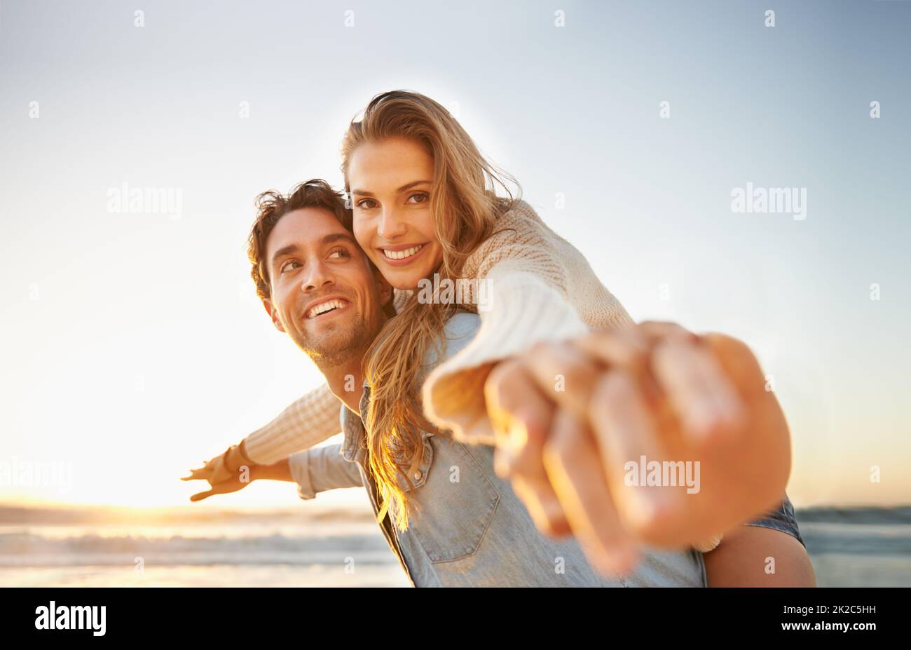 Wir feiern ihre Liebe. Ein glückseliges junges Paar, das gemeinsam ihre Liebe am Meer feiert. Stockfoto