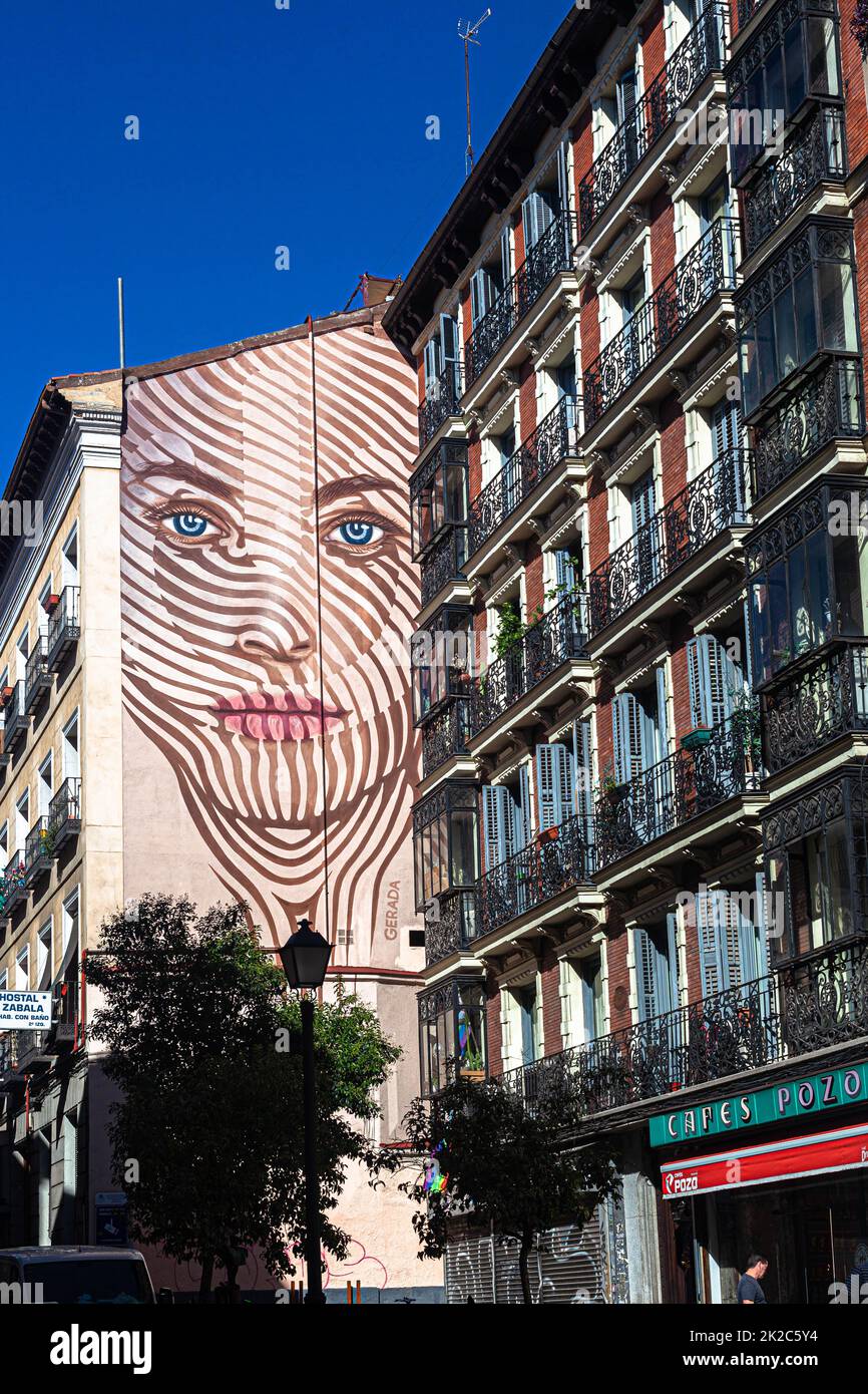 Großes Wandgemälde mit dem Gesicht einer Frau hoch auf der externen Parteiwand des Gebäudes, Calle de la Magdalena, Madrid, Spanien. Stockfoto