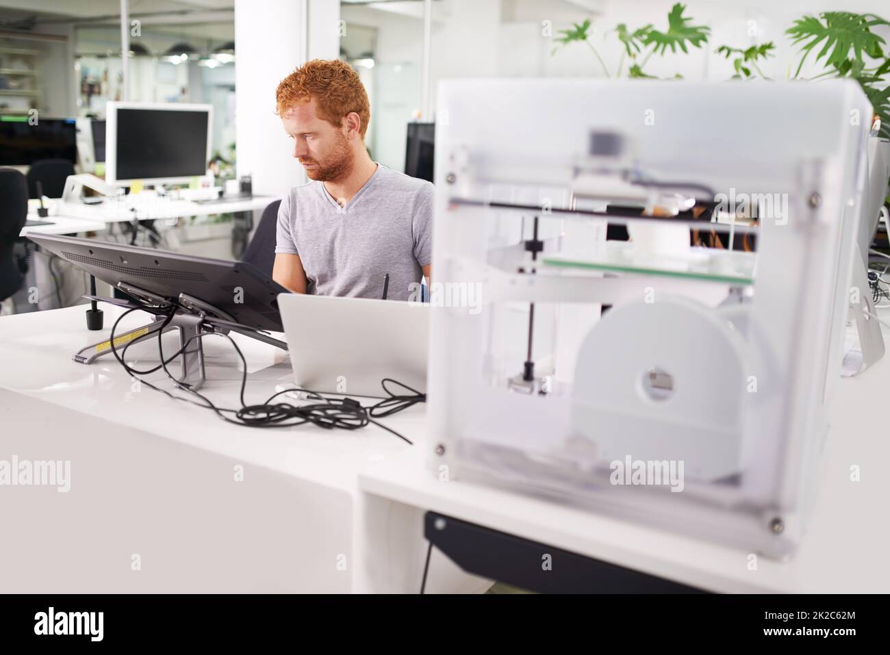 Es wird daran gearbeitet, einige Modelle zu drucken. Eine Aufnahme eines jungen Mannes, der seine Entwürfe auf einem Drucker aus dem Jahr 3D druckte. Stockfoto