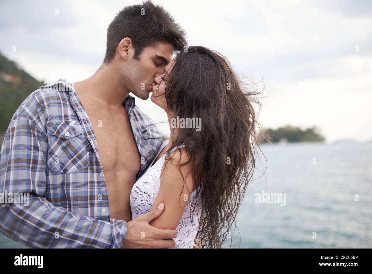 Ihre Liebe nach draußen nehmen. Aufnahme eines intimen jungen Paares, das einen Kuss am Wasser genießt. Stockfoto