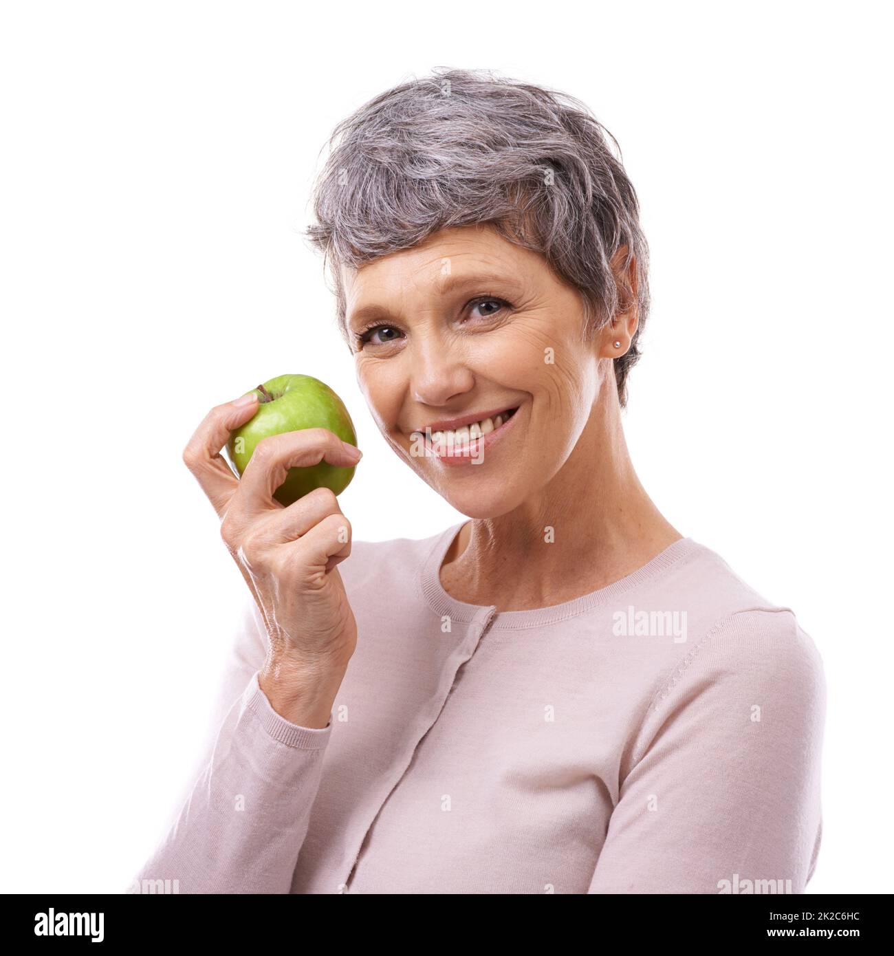 Ihr gesundes Leuchten erhalten. Studioporträt einer glücklichen reifen Frau, die einen auf Weiß isolierten Apfel hält. Stockfoto