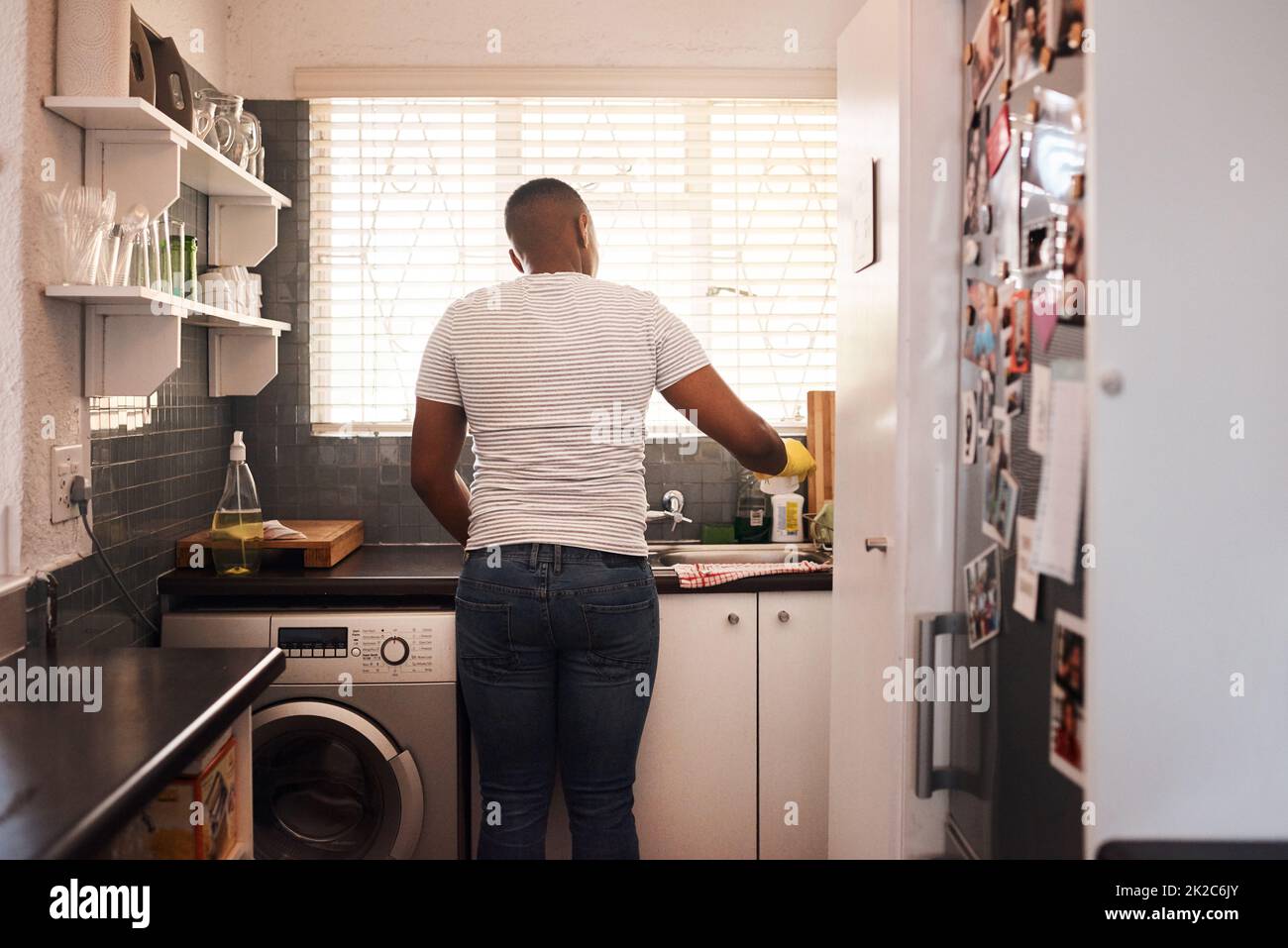 Eine saubere Küche ist besser als eine schmutzige. Rückansicht eines Mannes, der das Geschirr zu Hause macht. Stockfoto