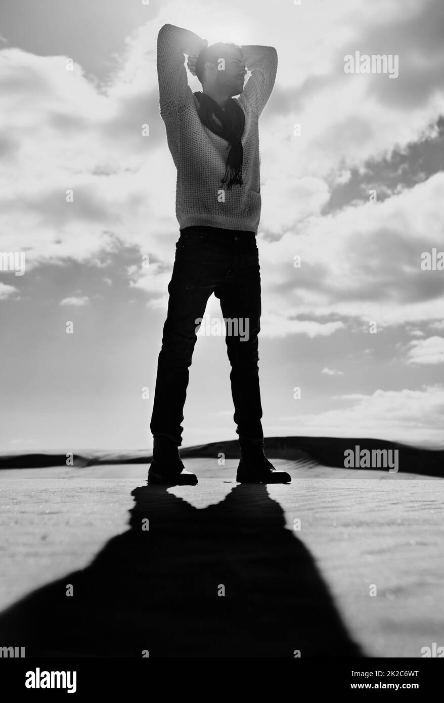 Der Mensch versus die Elemente. Einfarbige Ganzkörperaufnahme eines Mannes, der in einer Wüstenlandschaft steht. Stockfoto