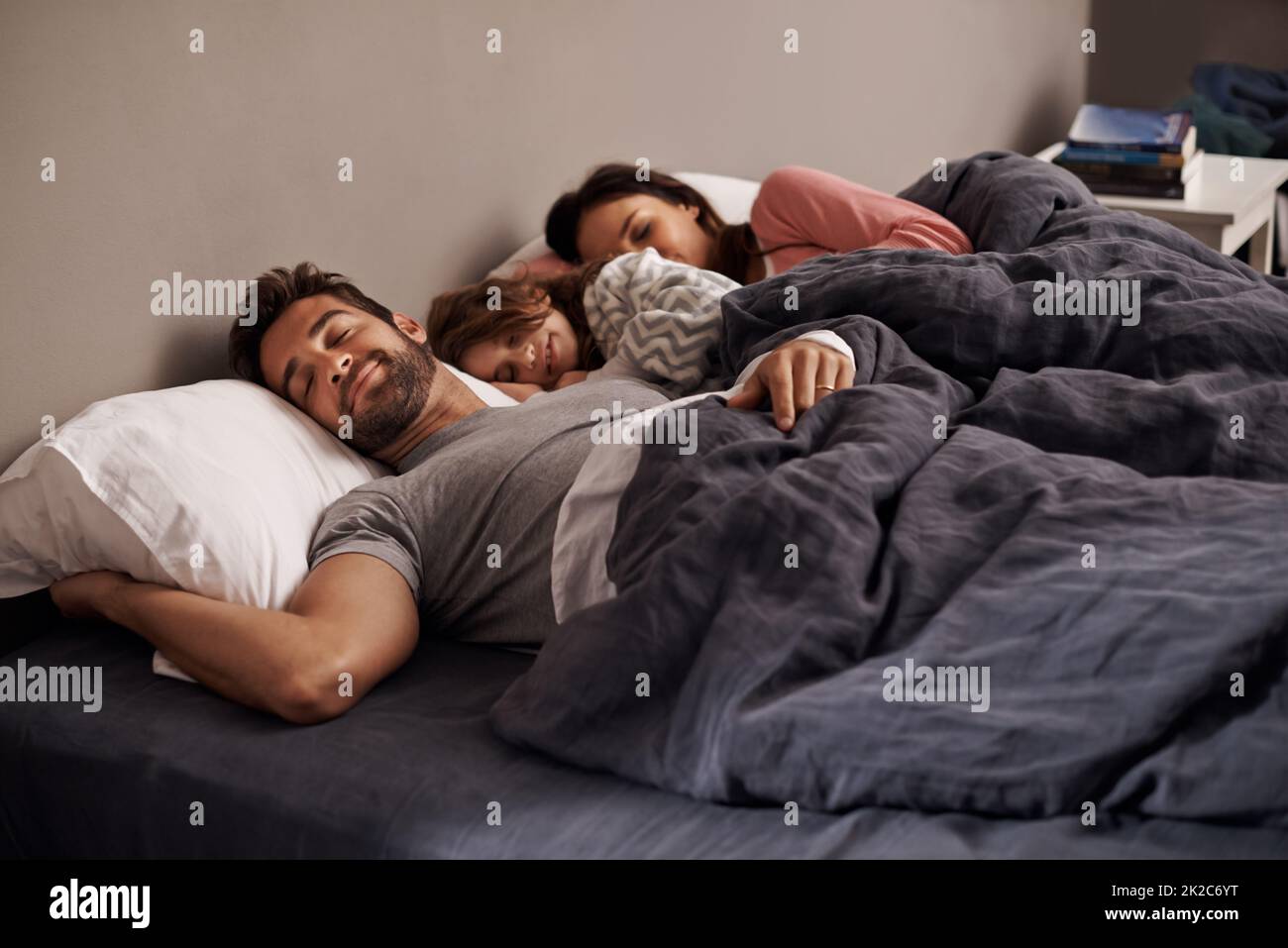 Das ist Glückseligkeit Aufnahme eines kleinen Mädchens, das neben ihren Eltern im Bett schläft. Stockfoto