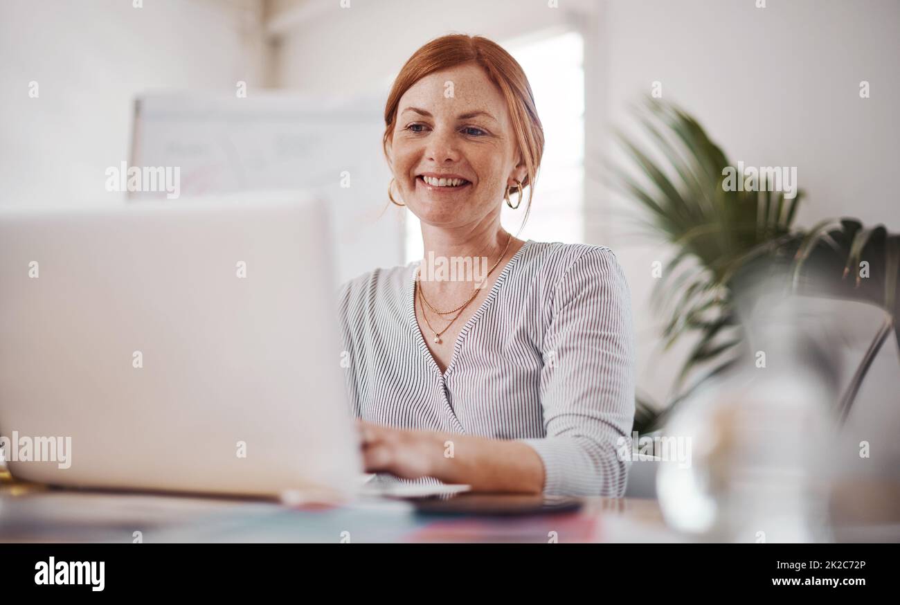 Erfolg gehört zu der harten Arbeit. Aufnahme einer reifen Geschäftsfrau, die in einem Büro an einem Laptop arbeitet. Stockfoto