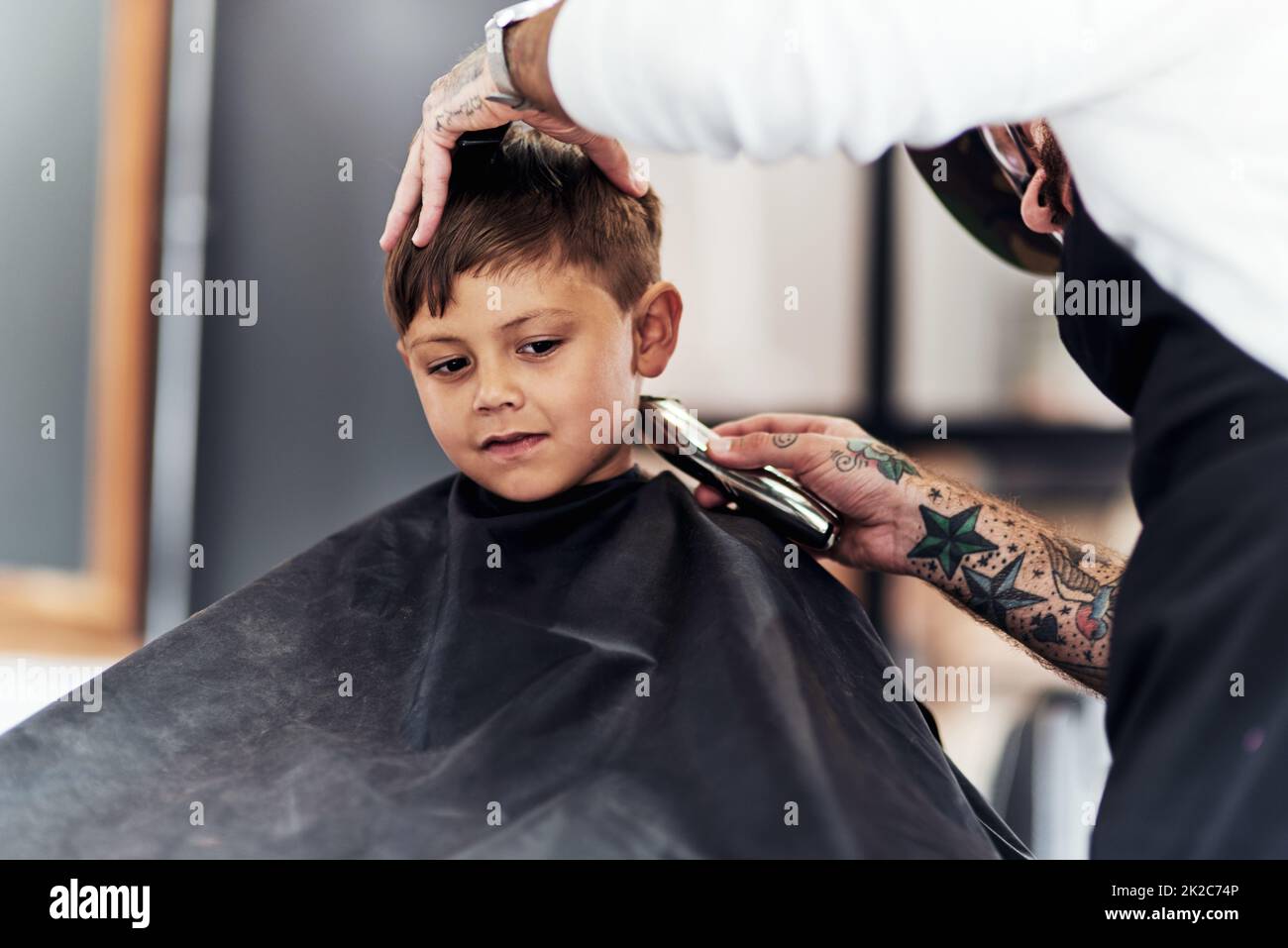Große Jungen weinen nicht, wenn sie einen Haarschnitt bekommen. Cropped schoss einen entzückenden kleinen Jungen, der im Friseurladen einen Haarschnitt bekommt. Stockfoto