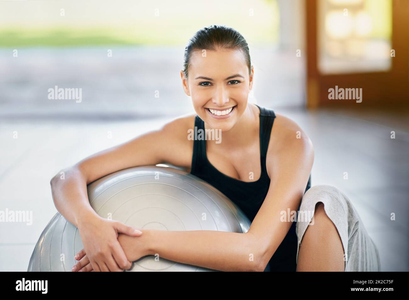 Was für ein tolles Workout. Beschnittenes Porträt einer jungen Frau, die gegen ihren Übungsball sitzt. Stockfoto