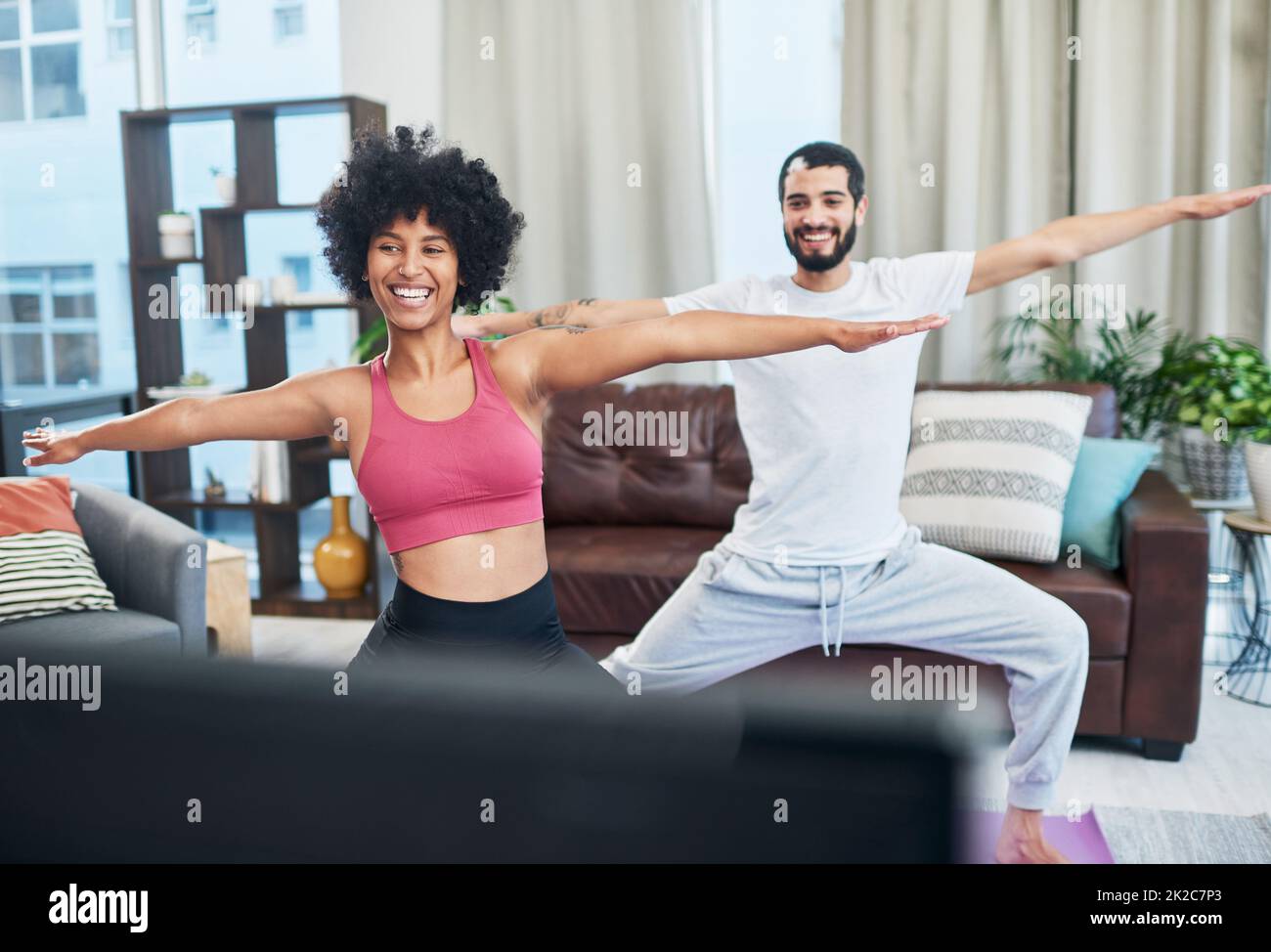 Aus diesem Video haben wir alles gelernt, was wir wissen. Aufnahme eines Paares, das beim Yoga-Üben zu Hause den Fernseher ansah. Stockfoto